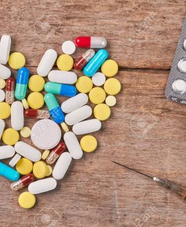Pills formed heart, narcotics, bottle. Concept of drug and alcohol addiction. Alcohol beverage and drugs on wooden background.